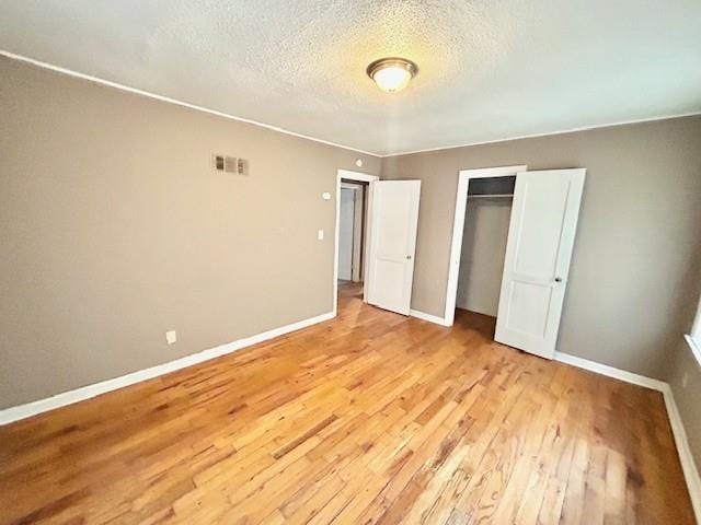 5046 Glenside Ct, Kansas City, MO 64129 - unfurnished bedroom featuring light wood finished floors, a closet, and a textured ceiling