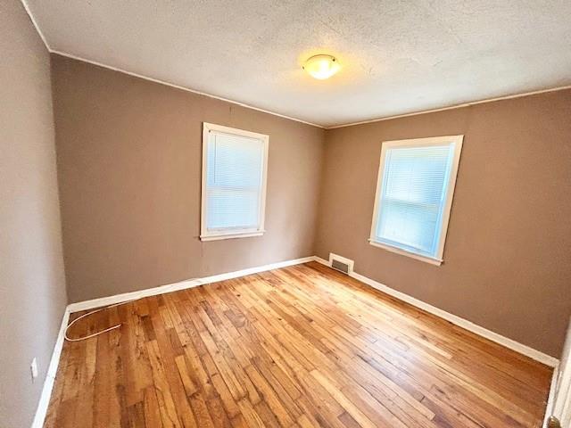 5046 Glenside Ct, Kansas City, MO 64129 - empty room with wood-type flooring, a textured ceiling, and crown molding