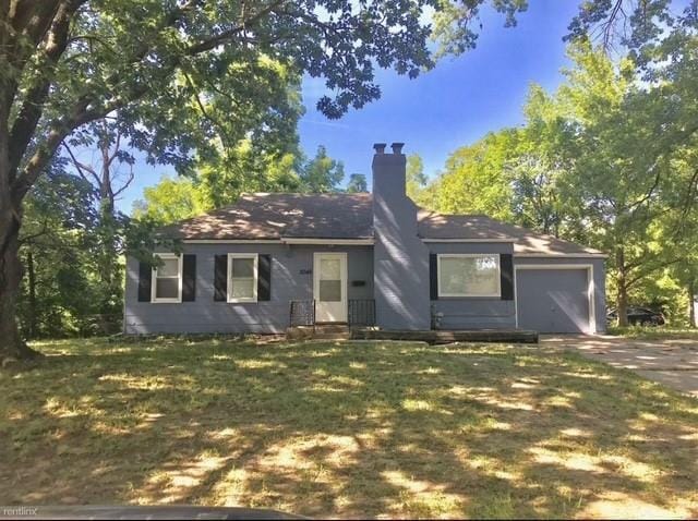 5046 Glenside Ct, Kansas City, MO 64129 - view of front of home featuring an attached garage, a chimney, concrete driveway, and a front lawn