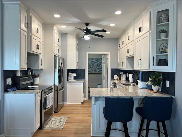 11681 S Roundtree St, Olathe, KS 66061 - kitchen featuring stainless steel appliances, a peninsula, a breakfast bar area, a ceiling fan, and backsplash