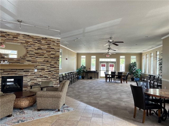 11681 S Roundtree St, Olathe, KS 66061 - tiled living room with crown molding, carpet floors, a textured ceiling, ceiling fan, and a stone fireplace