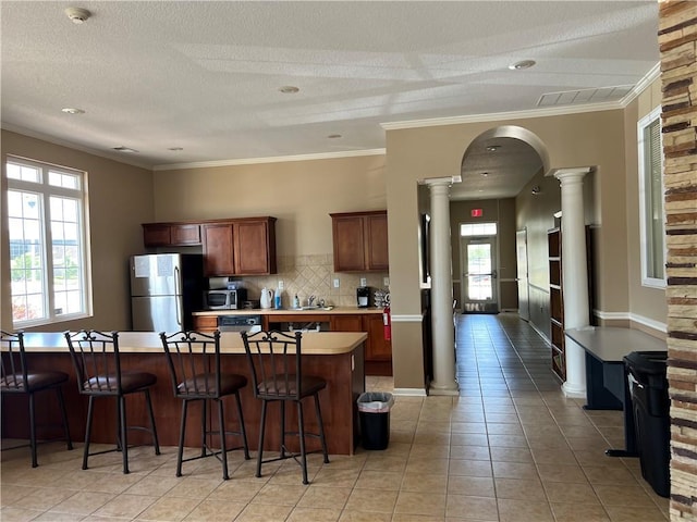 11681 S Roundtree St, Olathe, KS 66061 - kitchen featuring appliances with stainless steel finishes, decorative columns, light countertops, light tile patterned floors, and ornamental molding
