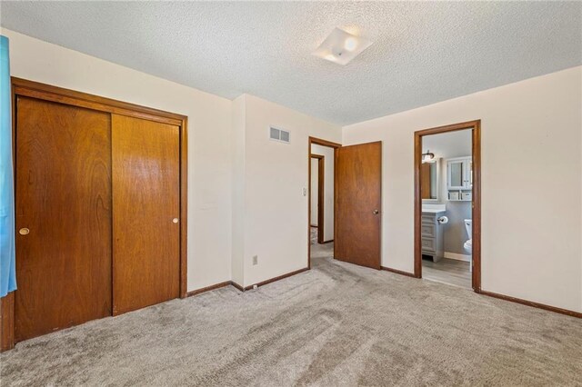 19308 E 18th St N, Independence, MO 64058 - unfurnished bedroom featuring carpet flooring, a closet, a textured ceiling, and ensuite bathroom