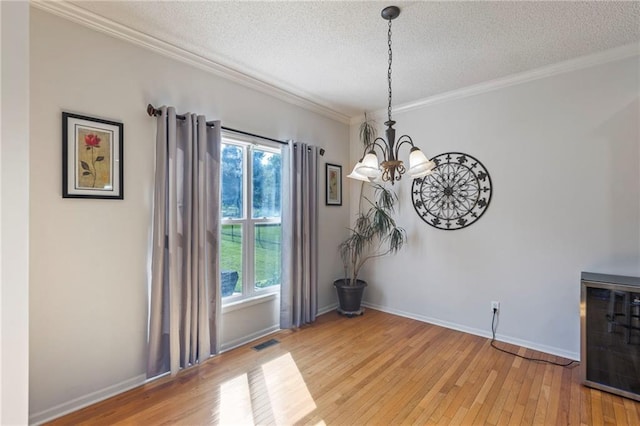 2712 SW Carlton Dr, Lees Summit, MO 64082 - unfurnished dining area with a chandelier, a textured ceiling, light wood-style floors, and ornamental molding