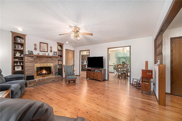 21830 155th St, Basehor, KS 66007 - living area with a textured ceiling, ceiling fan, light wood finished floors, a brick fireplace, and built in shelves