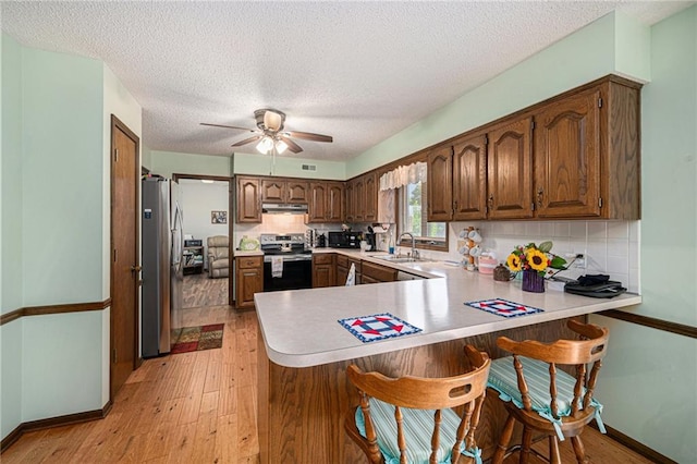 21830 155th St, Basehor, KS 66007 - kitchen featuring appliances with stainless steel finishes, a peninsula, a ceiling fan, light wood-style flooring, and backsplash