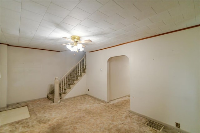1134 Atchison St, Atchison, KS 66002 - empty room with arched walkways, ornamental molding, stairs, a ceiling fan, and light carpet