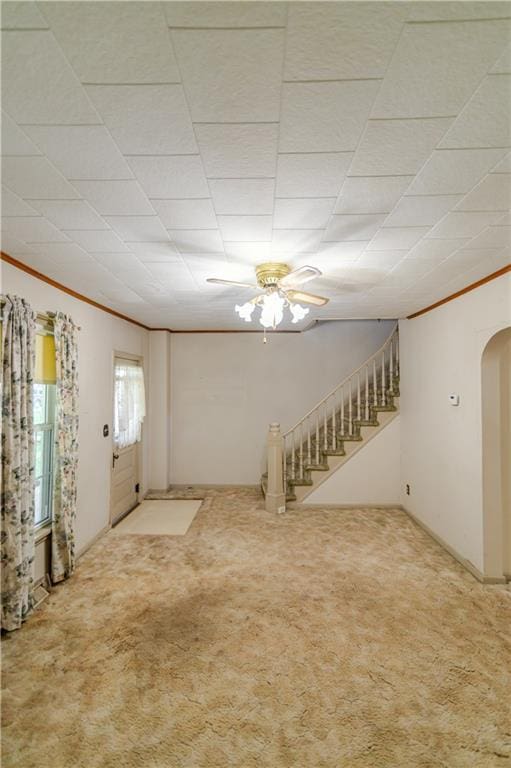 1134 Atchison St, Atchison, KS 66002 - below grade area featuring stairs, carpet flooring, crown molding, arched walkways, and a ceiling fan
