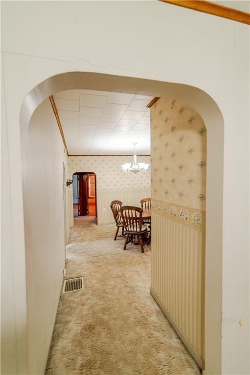 1134 Atchison St, Atchison, KS 66002 - hall featuring wallpapered walls, light colored carpet, arched walkways, and a chandelier