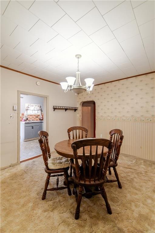 1134 Atchison St, Atchison, KS 66002 - carpeted dining room featuring a chandelier, ornamental molding, and arched walkways