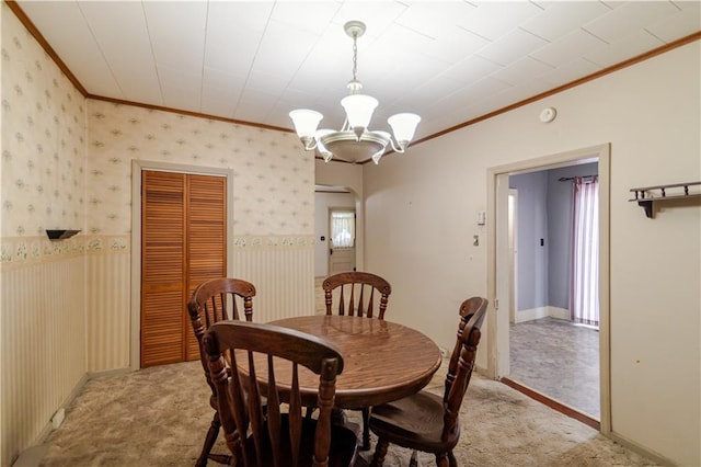 1134 Atchison St, Atchison, KS 66002 - dining space with crown molding, light colored carpet, a chandelier, and a wainscoted wall