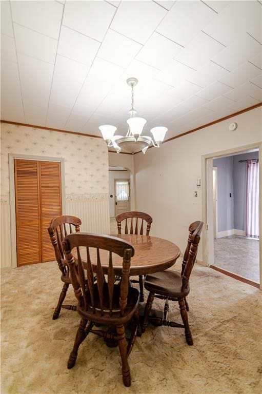 1134 Atchison St, Atchison, KS 66002 - carpeted dining room featuring crown molding, a chandelier, wallpapered walls, and wainscoting