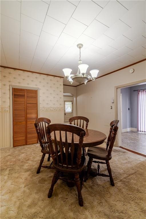 1134 Atchison St, Atchison, KS 66002 - dining room featuring ornamental molding, a chandelier, carpet, a wainscoted wall, and wallpapered walls