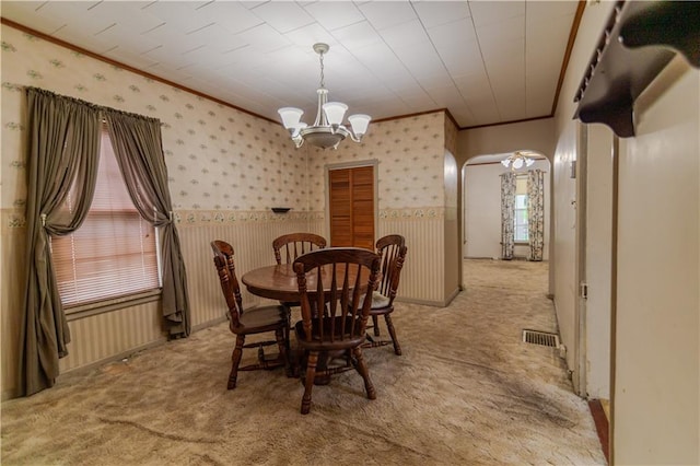 1134 Atchison St, Atchison, KS 66002 - dining space featuring ornamental molding, arched walkways, wainscoting, a chandelier, and light colored carpet