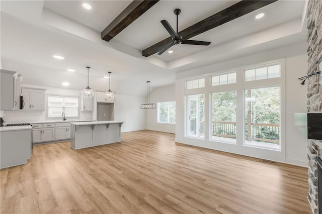 13491 Terrace Park Dr, Parkville, MO 64152 - kitchen featuring a center island, light wood-style flooring, a breakfast bar, a fireplace, and light countertops