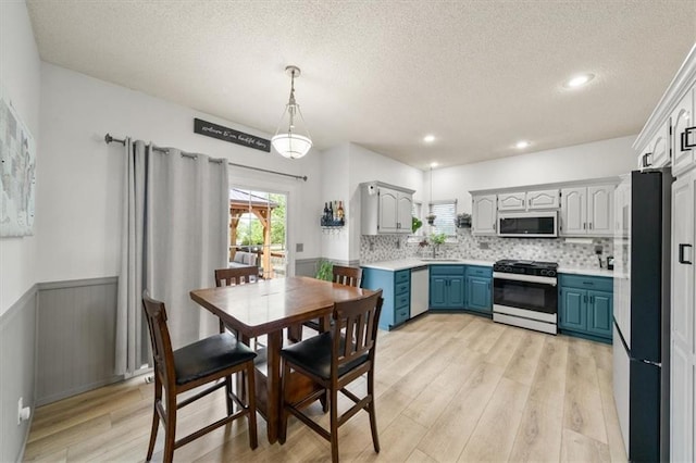 16122 W 157th St, Olathe, KS 66062 - dining room with light wood finished floors, a textured ceiling, a wainscoted wall, and recessed lighting