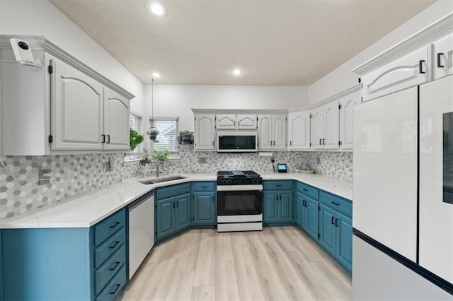 16122 W 157th St, Olathe, KS 66062 - kitchen with white appliances, blue cabinetry, light wood finished floors, light countertops, and tasteful backsplash