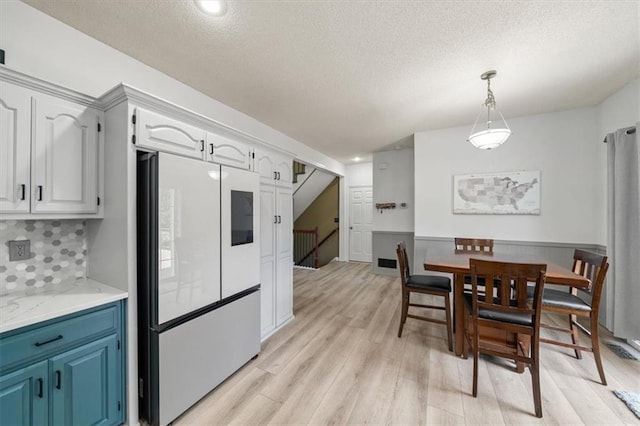 16122 W 157th St, Olathe, KS 66062 - dining space with light wood finished floors, a textured ceiling, and stairs