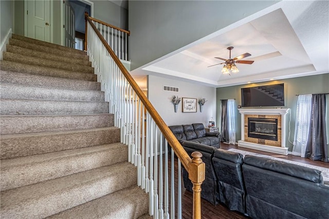 61 SW 446th Rd, Clinton, MO 64735 - stairs featuring a tray ceiling, a ceiling fan, wood finished floors, and a tile fireplace