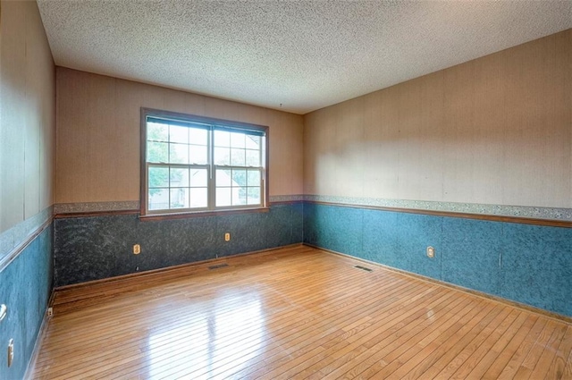 16327 W Locust St, Olathe, KS 66062 - unfurnished room featuring hardwood / wood-style floors, wainscoting, a textured ceiling, and wallpapered walls