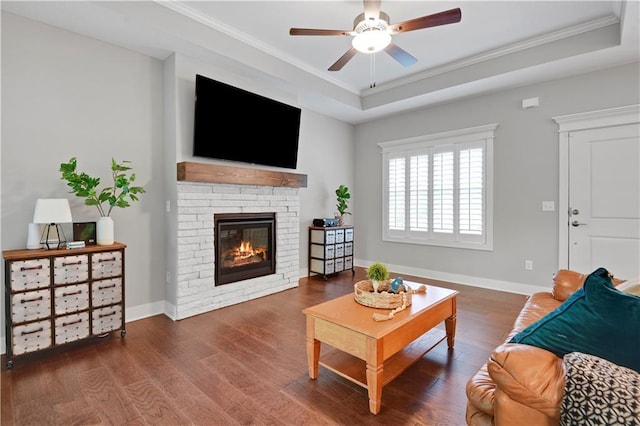 23103 W 125th Ter, Olathe, KS 66016 - living room featuring ornamental molding, wood finished floors, a ceiling fan, a glass covered fireplace, and a tray ceiling