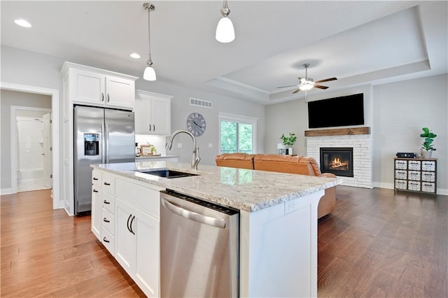 23103 W 125th Ter, Olathe, KS 66016 - kitchen with stainless steel appliances, a tray ceiling, a glass covered fireplace, ceiling fan, and light stone countertops