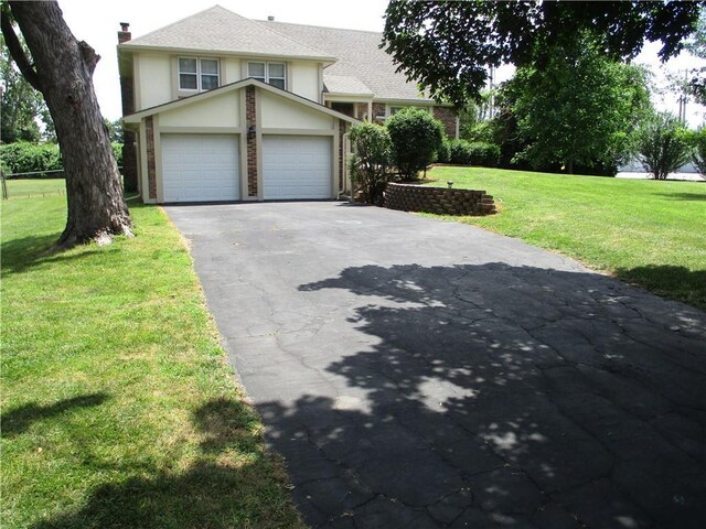 8265 Gleason Rd, Lenexa, KS 66227 - view of front of home featuring a front lawn, asphalt driveway, brick siding, and stucco siding