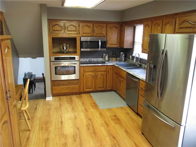 8265 Gleason Rd, Lenexa, KS 66227 - kitchen featuring appliances with stainless steel finishes, brown cabinets, backsplash, light countertops, and light wood-style floors