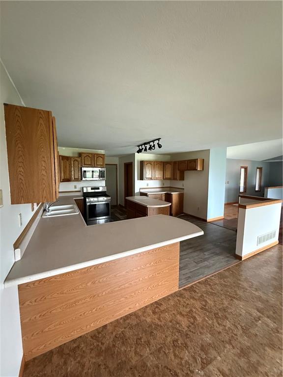 1011 N Arrowhead Dr, Burlington, KS 66839 - kitchen with stainless steel appliances, a peninsula, brown cabinets, and a center island