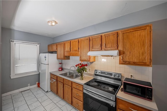 321 Oakley Ave, Kansas City, MO 64123 - kitchen with stainless steel range with electric stovetop, under cabinet range hood, freestanding refrigerator, and light countertops