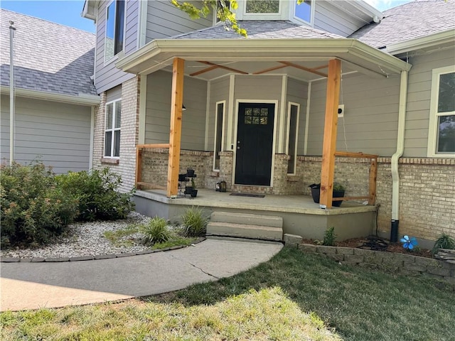 200 S Park Dr, Raymore, MO 64083 - view of exterior entry with covered porch, brick siding, and a shingled roof