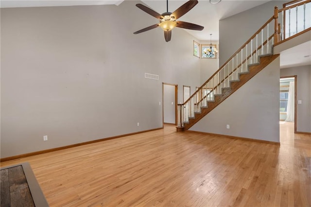 200 S Park Dr, Raymore, MO 64083 - unfurnished living room with stairs, wood finished floors, ceiling fan, and high vaulted ceiling
