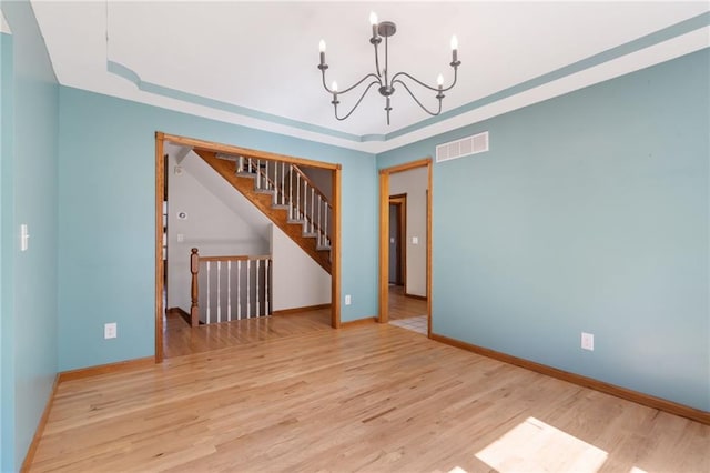 200 S Park Dr, Raymore, MO 64083 - spare room featuring a chandelier, a tray ceiling, wood finished floors, and stairs