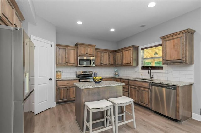 801 NW Hickory Ridge Dr, Grain Valley, MO 64029 - kitchen with appliances with stainless steel finishes, light wood-style floors, a center island, backsplash, and recessed lighting