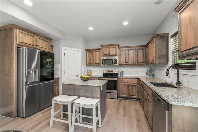 801 NW Hickory Ridge Dr, Grain Valley, MO 64029 - kitchen with appliances with stainless steel finishes, light wood-style floors, a kitchen island, tasteful backsplash, and recessed lighting