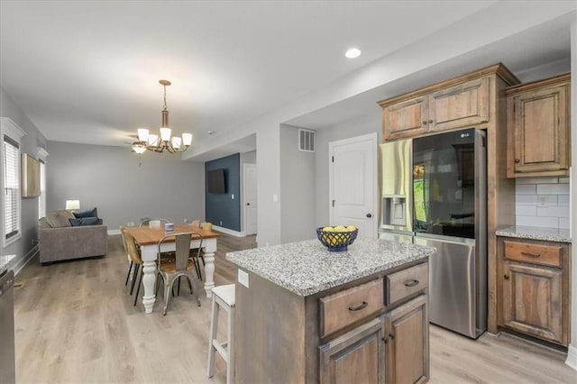 801 NW Hickory Ridge Dr, Grain Valley, MO 64029 - kitchen with stainless steel refrigerator with ice dispenser, open floor plan, a chandelier, light wood-style flooring, and a kitchen island