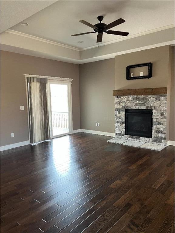 15653 Lakeside Dr, Basehor, KS 66007 - unfurnished living room featuring a raised ceiling, crown molding, hardwood / wood-style flooring, a ceiling fan, and a stone fireplace
