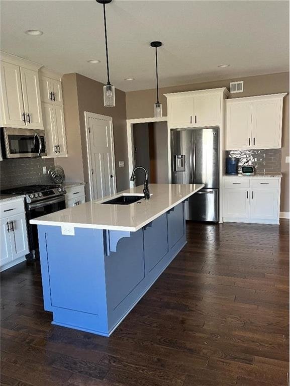 15653 Lakeside Dr, Basehor, KS 66007 - kitchen with stainless steel appliances, backsplash, dark wood-style flooring, white cabinetry, and recessed lighting