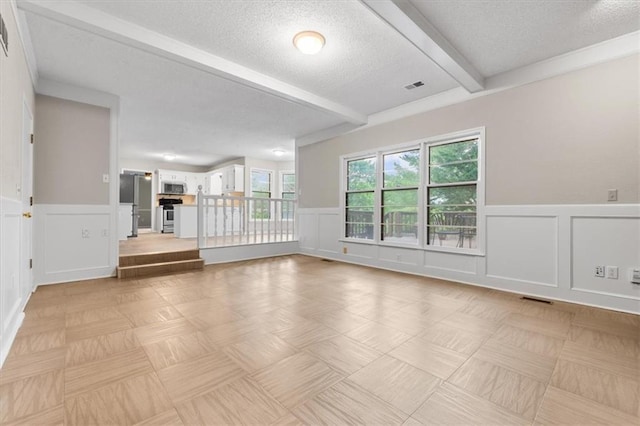 13942 W 113th St, Olathe, KS 66215 - unfurnished living room featuring beam ceiling, a wainscoted wall, a decorative wall, a textured ceiling, and a fireplace