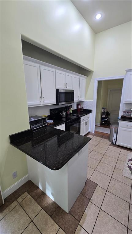 16810 NE 170th Ter, Holt, MO 64048 - kitchen with stainless steel microwave, black electric range oven, a high ceiling, white cabinets, and a peninsula
