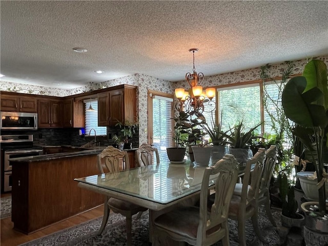 505 Williamsburg Dr, Lees Summit, MO 64063 - dining room with a chandelier, wallpapered walls, a textured ceiling, plenty of natural light, and wood finished floors