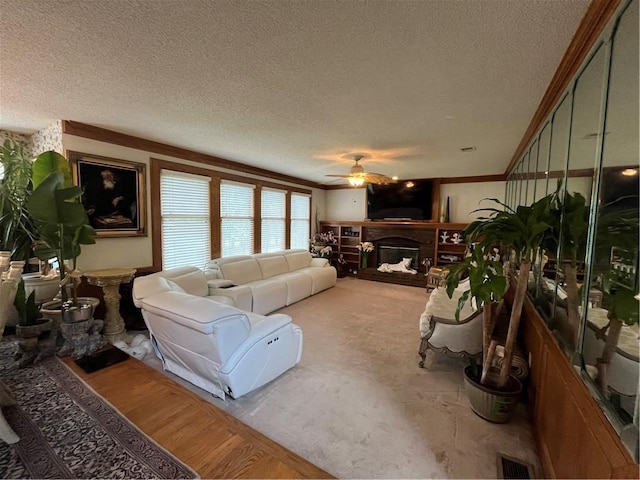 505 Williamsburg Dr, Lees Summit, MO 64063 - living area with a textured ceiling, a ceiling fan, a fireplace with raised hearth, and crown molding