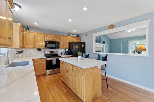 1903 NW Rosewood Dr, Grain Valley, MO 64029 - kitchen with black appliances, light wood-style flooring, decorative backsplash, a kitchen bar, and a kitchen island