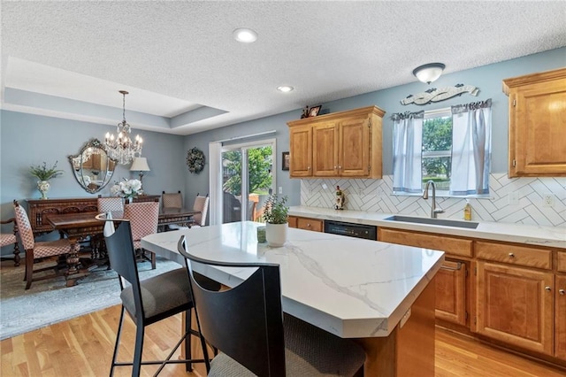 1903 NW Rosewood Dr, Grain Valley, MO 64029 - kitchen featuring healthy amount of natural light, a breakfast bar, light wood-style flooring, decorative backsplash, and a textured ceiling