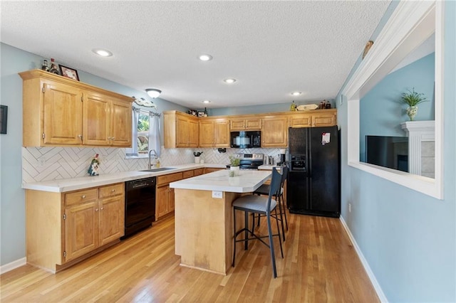 1903 NW Rosewood Dr, Grain Valley, MO 64029 - kitchen featuring black appliances, a breakfast bar, tasteful backsplash, a textured ceiling, and light countertops