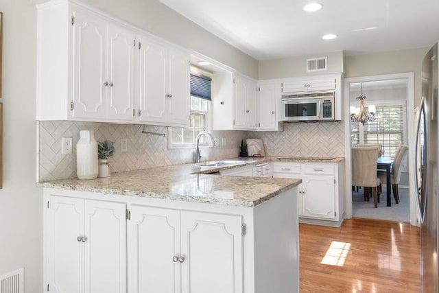 5501 W 86th St, Overland Park, KS 66207 - kitchen with appliances with stainless steel finishes, healthy amount of natural light, white cabinets, a peninsula, and recessed lighting