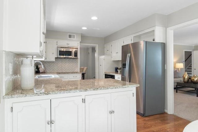 5501 W 86th St, Overland Park, KS 66207 - kitchen featuring appliances with stainless steel finishes, a peninsula, backsplash, white cabinets, and light wood-style floors