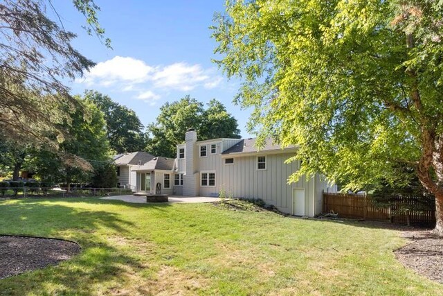 5501 W 86th St, Overland Park, KS 66207 - rear view of house with board and batten siding, a patio area, and a chimney