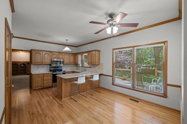 13217 S Locust St, Olathe, KS 66062 - kitchen with stainless steel appliances, a peninsula, backsplash, light countertops, and brown cabinetry