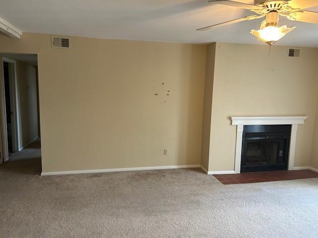 3600 Gabriel Ave Unit 303, Parsons, KS 67357 - unfurnished living room featuring carpet floors, a fireplace with flush hearth, and a ceiling fan